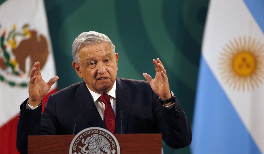 Mexican President Andrés Manuel López Obrador gives his daily, morning press conference at the National Palace in Mexico City, Tuesday, Feb. 23, 2021, with an Argentine flag in the background, right, as Argentine President Alberto Fernandez attends the event. (AP Photo/Marco Ugarte)