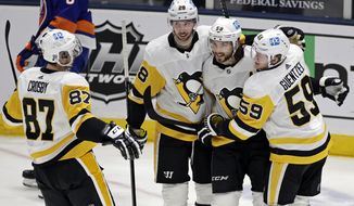 Pittsburgh Penguins defenseman Kris Letang (58) is congratulated by teammates after scoring a goal during the second period of the team&#39;s NHL hockey game against the New York Islanders, Saturday, Feb. 27, 2021, in Uniondale, N.Y. (AP Photo/Adam Hunger)
