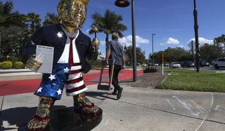 Tommy Zegan walks away after moving his golden Donald Trump statue across the street from CPAC at the Hyatt Regency in Orlando, Fla on Sunday, Feb. 28, 2021. (Sam Thomas/Orlando Sentinel via AP)