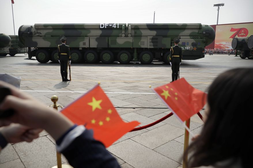 In this Oct. 1, 2019, file photo, spectators wave Chinese flags as military vehicles carrying DF-41 ballistic missiles roll during a parade to commemorate the 70th anniversary of the founding of Communist China in Beijing. (AP Photo/Mark Schiefelbein) ** FILE **