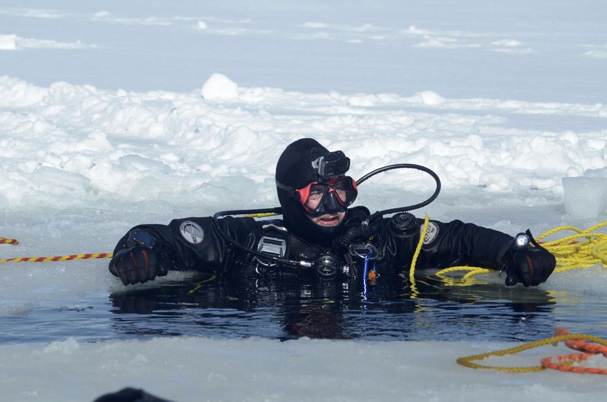 In a photo from Feb. 21, 2021, diver Matt Hunt stretches his arms across the ice during a training dive Sunday at Goguac Lake in Battle Creek, Mich. Several members of Calhoun County's Area Law Enforcement Underwater Recovery Team (ALURT) were under eight inches of ice and taking a look around. "It is really nice. Once you get past the initial shock on your face, the water temperature is actually warmer than we are standing right here," Andy Erard said. "We do this once a year usually in February." (Trace Christenson/Battle Creek Enquirer via AP)