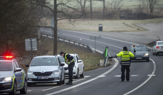Police officers check cars on a road between the towns, Ceske Budejovice and Cesky Krumlov, near Kosov, Czech Republic, Monday, March 1, 2021. Limits for free movement of people are set in place in the Czech Republic. Travelling to other counties unless they go to work or have to take care about relatives is prohibited.(Vaclav Pancer/CTK via AP)
