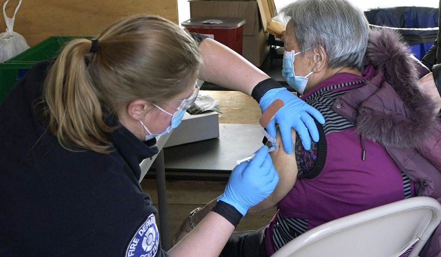 Kristin May, left, an EMT with the Seattle Fire Dept., gives the first dose of the Moderna COVID-19 vaccine to Nu Xiao Jiang, right, Monday, March 1, 2021, at a City of Seattle community COVID-19 testing and vaccination clinic in Seattle's Rainier Beach neighborhood. Seattle Mayor Jenny Durkan announced Monday that the city's COVID-19 vaccination efforts would be expanding in the coming weeks as more doses become available, including the use of the events center at Lumen Field — the home of the NFL football Seattle Seahawks and the MLS soccer Seattle Sounders — as a mass vaccination site with the capacity to deliver thousands of doses every day. (AP Photo/Ted S. Warren)