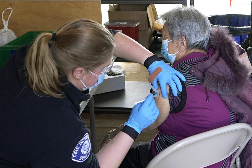 Kristin May, left, an EMT with the Seattle Fire Dept., gives the first dose of the Moderna COVID-19 vaccine to Nu Xiao Jiang, right, Monday, March 1, 2021, at a City of Seattle community COVID-19 testing and vaccination clinic in Seattle's Rainier Beach neighborhood. Seattle Mayor Jenny Durkan announced Monday that the city's COVID-19 vaccination efforts would be expanding in the coming weeks as more doses become available, including the use of the events center at Lumen Field — the home of the NFL football Seattle Seahawks and the MLS soccer Seattle Sounders — as a mass vaccination site with the capacity to deliver thousands of doses every day. (AP Photo/Ted S. Warren)