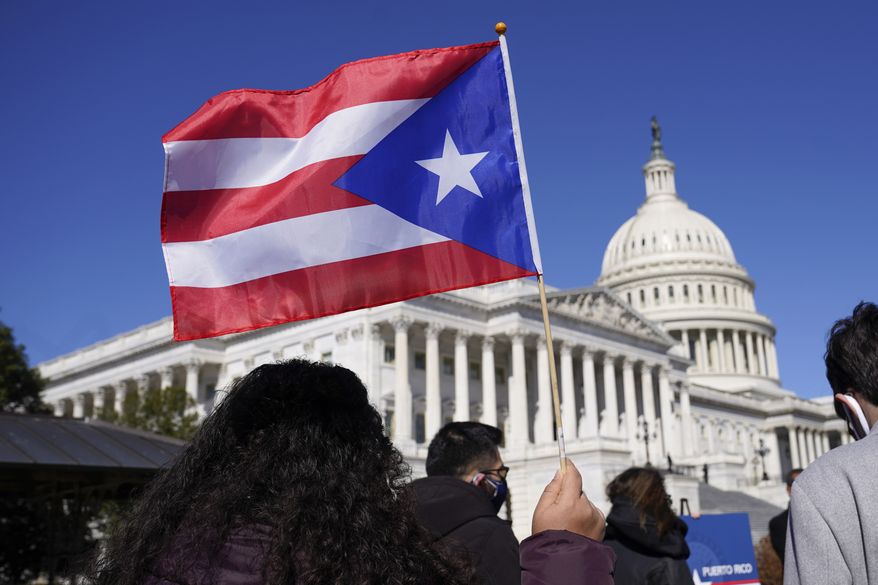 A woman waves the flag of Puerto Rico during a news conference on Puerto Rican statehood on Capitol Hill in Washington, Tuesday, March 2, 2021. (AP Photo/Patrick Semansky)