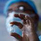 An Iraqi medical worker holds a vial of the Sinopharm coronavirus vaccine before starting the vaccination of health personnel, at a clinic in Baghdad, Iraq, Tuesday, March 2, 2021. (AP/Photo/Hadi Mizban)