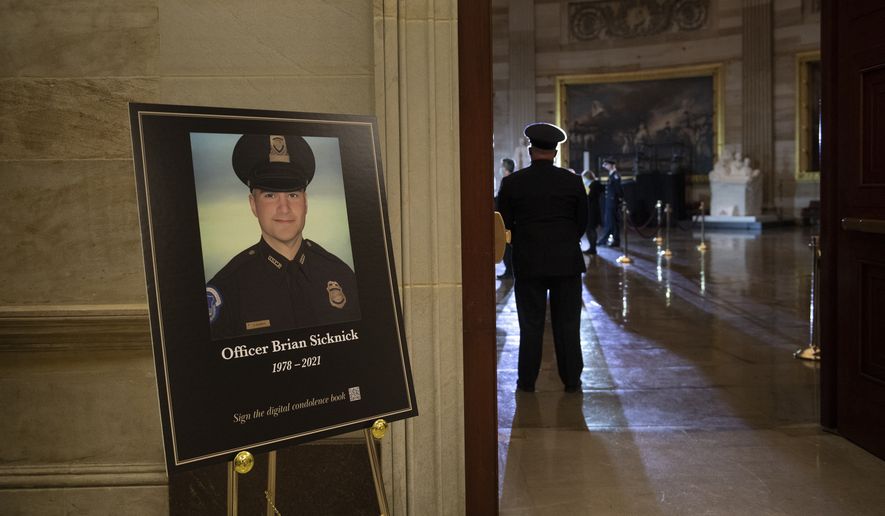 In this Feb. 2, 2021, photo, a placard is displayed with an image of the late U.S. Capitol Police Officer Brian Sicknick on it as people wait for an urn with his cremated remains to be carried into the U.S. Capitol to lie in honor in the Capitol Rotunda in Washington. (Brendan Smialowski/Pool via AP) **FILE**