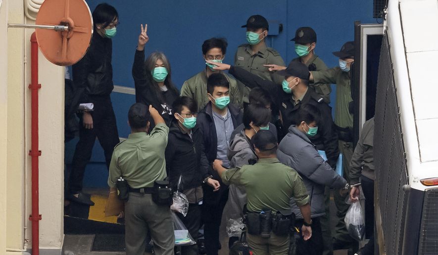 Former lawmaker Leung Kwok-hung, known as "Long Hair," second left, shows a victory sign and some of the 47 pro-democracy activists are escorted by Correctional Services officers to a prison van in Hong Kong, Thursday, March 4, 2021. A marathon court hearing for 47 pro-democracy activists in Hong Kong charged with conspiracy to commit subversion enters its fourth day on Thursday, as the court deliberates over whether the defendants will be granted bail. (AP Photo/Kin Cheung)