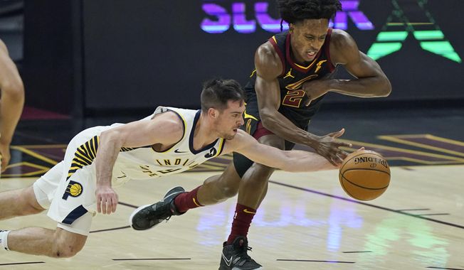 Indiana Pacers&#x27; T.J. McConnell, left, and Cleveland Cavaliers&#x27; Collin Sexton reach for the ball during the first half of an NBA basketball game Wednesday, March 3, 2021, in Cleveland. (AP Photo/Tony Dejak)