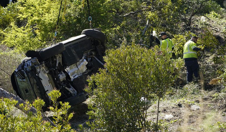 Workers collect debris beside a vehicle after a rollover accident involving golfer Tiger Woods Tuesday, Feb. 23, 2021, in Rancho Palos Verdes, Calif., a suburb of Los Angeles. Woods suffered leg injuries in the one-car accident and was undergoing surgery, authorities and his manager said. (AP Photo/Marcio Jose Sanchez)