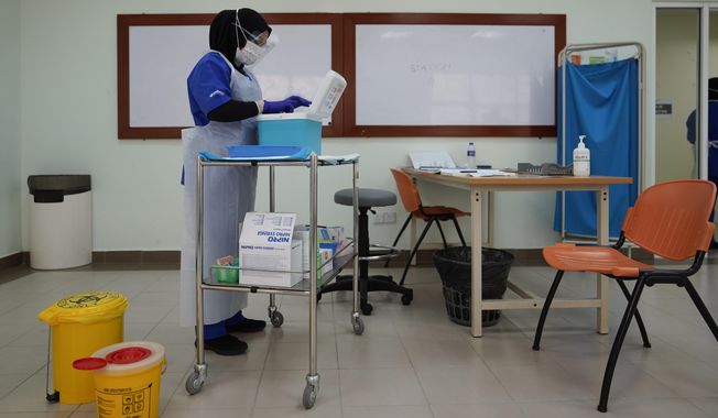 A health worker prepares to administer the Pfizer's COVID-19 vaccine to a health staff member at the Hospital UiTM in Sungai Buloh, outskirts of Kuala Lumpur, Malaysia, Wednesday, March 3, 2021. (AP Photo/Vincent Thian)