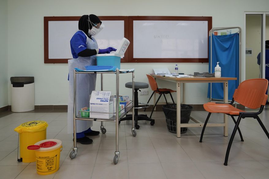 A health worker prepares to administer the Pfizer's COVID-19 vaccine to a health staff member at the Hospital UiTM in Sungai Buloh, outskirts of Kuala Lumpur, Malaysia, Wednesday, March 3, 2021. (AP Photo/Vincent Thian)