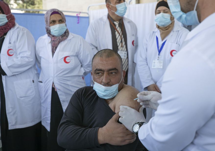 FILE - In this Feb. 3, 2021 file photo, a medic administers a Moderna COVID-19 vaccine to a fellow medic during a campaign to vaccinate front-line medical workers, at the health ministry, in the West Bank city of Bethlehem. The Palestinian Authority's decision to divert some of its tiny stockpile of coronavirus vaccines to senior officials, soccer players and others has sparked controversy, feeding into long-standing concerns about corruption as it struggles to respond to a worsening outbreak. (AP Photo/Nasser Nasser, File)