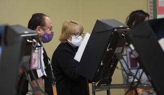 A technician watches as a poll worker tries to use a voting machine after experiencing issues in Georgia&#39;s Senate runoff elections at a senior center, Tuesday, Jan. 5, 2021, in Acworth, Ga. (AP Photo/Branden Camp) ** FILE **