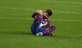 Barcelona&#39;s Gerard Pique holds his knee after getting injured during the the Copa del Rey semifinal, second leg, soccer match between FC Barcelona and Sevilla FC at the Camp Nou stadium in Barcelona, Spain, Wednesday March 3, 2021. (AP Photo/Joan Monfort)