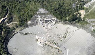 This photo provided by Aeromed shows the collapsed Radio Telescope in Arecibo, Puerto Rico, Tuesday, Dec. 1, 2020. The already damaged radio telescope that has played a key role in astronomical discoveries for more than half a century completely collapsed, falling onto the northern portion of the vast reflector dish more than 400 feet below. (Yamil Rodriguez/Aeromed via AP)