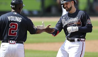 Atlanta Braves Ender Inciarte, right, gets five from first base coach Eric Young, left, after hitting a single against the Minnesota Twins during the third inning of an MLB spring training game Tuesday, March 2, 2021, in North Port, Fla. (Curtis Compton/Atlanta Journal-Constitution via AP)