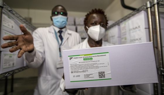Technicians show a carton of AstraZeneca COVID-19 vaccine manufactured by the Serum Institute of India, inside a cold storage room at the central vaccine depot in Kitengela town on the outskirts of Nairobi, in Kenya Thursday, March 4, 2021. Around 1.02 million doses of the AstraZeneca COVID-19 vaccine arrived in the country on Wednesday as part of the COVAX facility. (AP Photo/Ben Curtis)