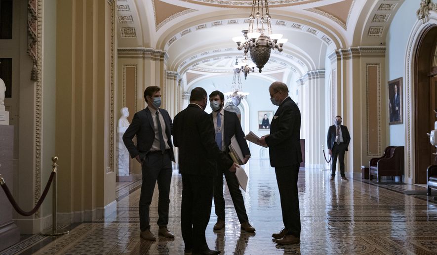 Congressional staffers wait in the ornate corridor outside the Senate chamber during a delay in work on the Democrats&#39; $1.9 trillion COVID-19 relief bill, at the Capitol in Washington, Friday, March 5, 2021. (AP Photo/J. Scott Applewhite)