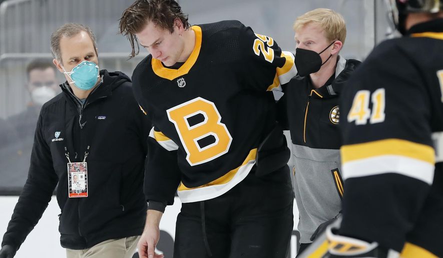 Boston Bruins&#39; Brandon Carlo is helped off the ice after an injury in the first period of an NHL hockey game against the Washington Capitals, Friday, March 5, 2021, in Boston. (AP Photo/Michael Dwyer)