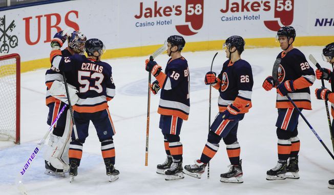 New York Islanders goalie Semyon Varlamov, left, is congratulated by teammates after their 5-2 win over the Buffalo Sabres in an NHL hockey game, Saturday, March 6, 2021, in Uniondale, NY. (AP Photo/Kevin Hagen).