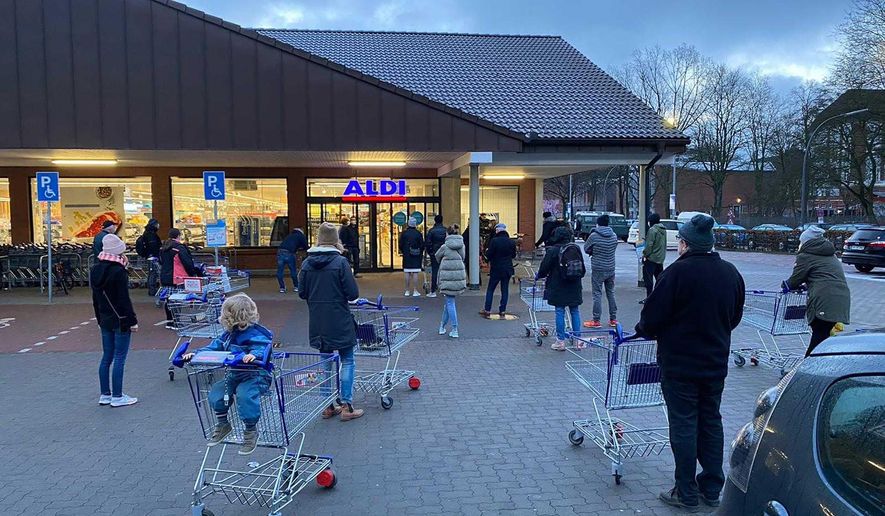 Customers wait for the opening of a branch of the German discounter &#x27;Aldi&#x27; in Hamburg, Germany, Saturday, March 6, 2021. From Saturday the discounter offers new coronavirus, COVID-19, quick tests for sale. (Haller/dpa via AP)