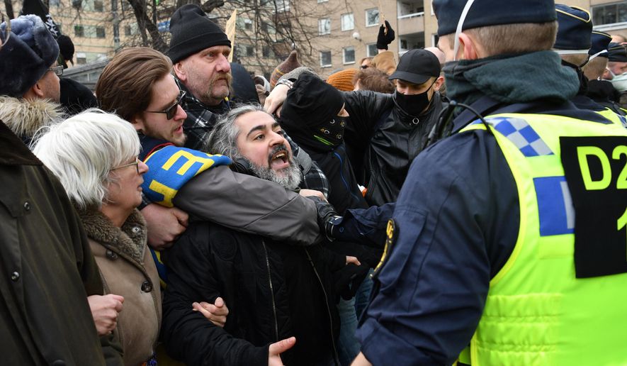 Anti-lockdown protesters face police during a demonstration against the coronavirus restrictions in Stockholm Saturday March 6, 2021. The protest was disbanded by police due to lack of permit for the public gathering. (Henrik Montgomery / TT via AP)