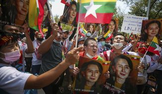 Myanmar nationals living in Thailand hold pictures of deposed Myanmar leader Aung San Suu Kyi as they protest against the military coup in front of the United Nations building in Bangkok, Thailand, Sunday, March 7, 2021. (AP Photo/Nava Sangthong)
