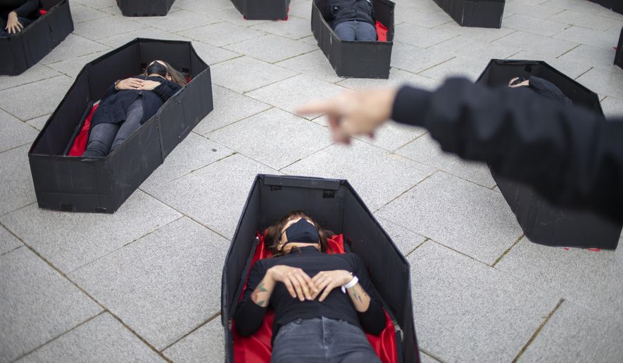 Women laying in coffins representing women killed in domestic violence during an event for upcoming International Women&#x27;s Day in front of Tel Aviv&#x27;s district court, Israel, Sunday, March 7, 2021. (AP Photo/Ariel Schalit)
