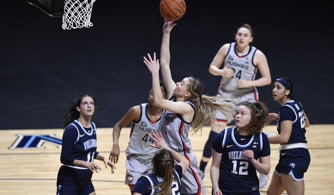 Connecticut&#x27;s Paige Bueckers, center, shoots as Villanova&#x27;s Bella Runyan (32) defends during the first half of an NCAA college basketball game in the Big East tournament semifinals at Mohegan Sun Arena, Sunday, March 7, 2021, in Uncasville, Conn. (AP Photo/Jessica Hill)