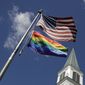 In this Friday, April 19, 2019 file photo, a gay pride rainbow flag flies with the U.S. flag in front of the Asbury United Methodist Church in Prairie Village, Kan.  (AP Photo/Charlie Riedel)  **FILE**