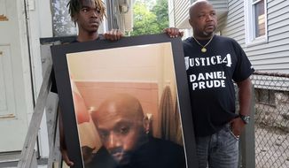 CORRECTS TO BROTHER NOT UNCLE OF DANIEL PRUDE - FILE - In this Sept. 3, 2020, file photo, Joe Prude, right, brother of Daniel Prude, and Daniel&#x27;s nephew Armin, stand with a picture of Daniel Prude in Rochester, N.Y. In a decision announced Tuesday, Feb. 23, 2021, a grand jury voted not to charge officers shown on body camera video holding Daniel Prude down naked and handcuffed on a city street last winter until he stopped breathing. (AP Photo/Ted Shaffrey, File)