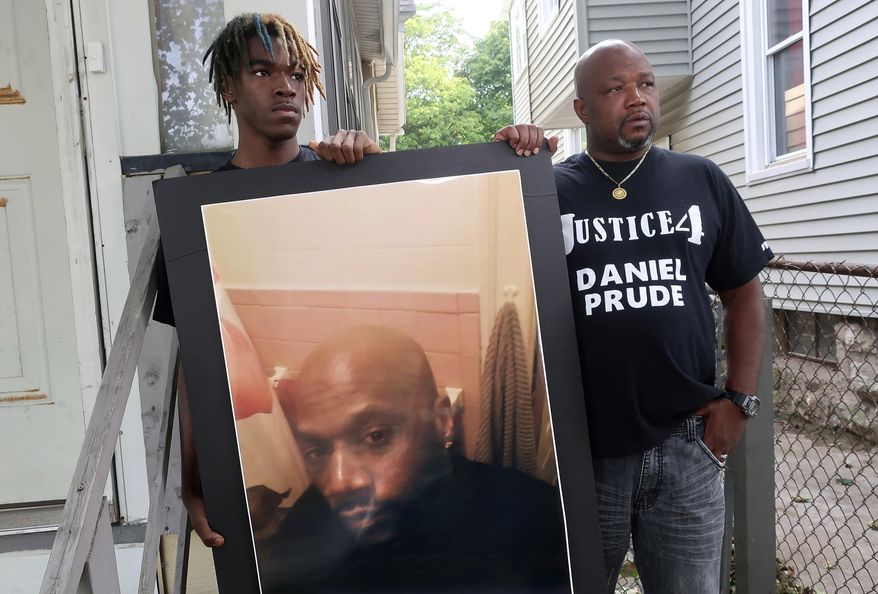 CORRECTS TO BROTHER NOT UNCLE OF DANIEL PRUDE - FILE - In this Sept. 3, 2020, file photo, Joe Prude, right, brother of Daniel Prude, and Daniel&#39;s nephew Armin, stand with a picture of Daniel Prude in Rochester, N.Y. In a decision announced Tuesday, Feb. 23, 2021, a grand jury voted not to charge officers shown on body camera video holding Daniel Prude down naked and handcuffed on a city street last winter until he stopped breathing. (AP Photo/Ted Shaffrey, File)