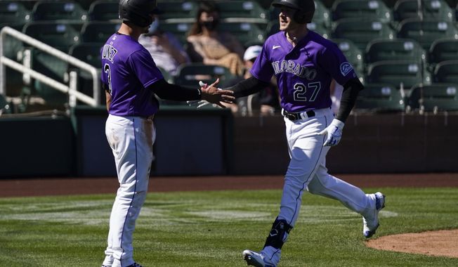 Colorado Rockies&#x27; Trevor Story (27) high-fives Dom Nunez (3) after scoring a three run homer during the third inning of a spring training baseball game against the Milwaukee Brewers Friday, March 5, 2021, in Scottsdale, Ariz. (AP Photo/Ashley Landis)