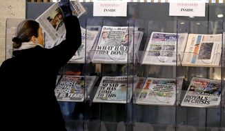 A customer takes a copy of a newspaper headlining Prince Harry and Meghan’s explosive TV interview at a newspaper stand outside a shop in London, Tuesday, March 9, 2021. Britain&#39;s royal family is absorbing the tremors from a sensational television interview by Prince Harry and the Duchess of Sussex, in which the couple said they encountered racist attitudes and a lack of support that drove Meghan to thoughts of suicide. (AP Photo/Frank Augstein)