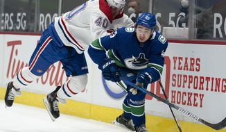Vancouver Canucks defenseman Quinn Hughes (43) fights for control of the puck with Montreal Canadiens right wing Joel Armia (40) during first-period NHL hockey game action in Vancouver, British Columbia, Monday, March 8, 2021. (Jonathan Hayward/The Canadian Press via AP)