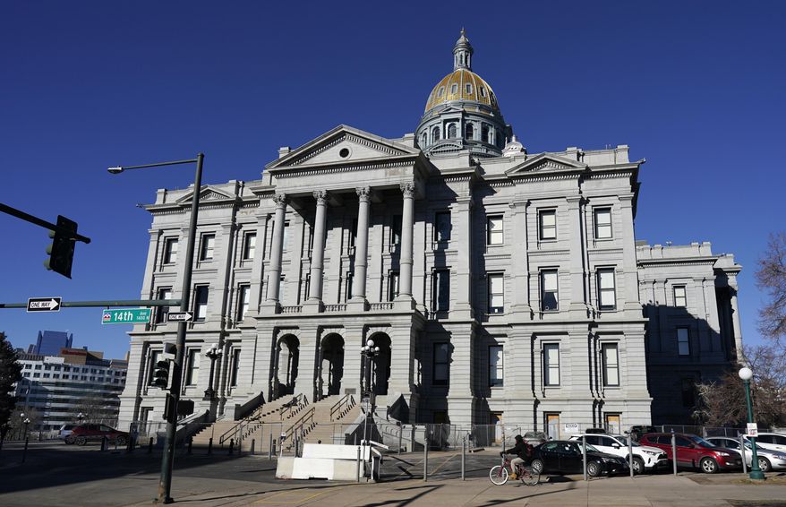 FILE - In this Jan. 15, 2021, file photo, a lone cyclist passes by Colorado's State Capitol in Denver. Colorado's Democrat-controlled House has passed legislation requiring firearms to be securely stored to prevent youths and other unauthorized persons from accessing them. The vote on Tuesday, March 9, 2021, virtually along party lines, came after 10 hours of debate on Monday in which Democrats repeatedly rejected efforts by Republican lawmakers to modify the measure. (AP Photo/David Zalubowski, File)