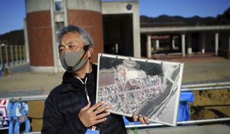 Noriyuki Suzuki, a volunteer who lost his 12-year-old daughter in a tsunami in 2011, tells his experience to a group of visitors in front of former Okawa Elementary School where 74 children from the elementary school lost their lives along with 10 teachers by the tsunami in Ishinomaki, Miyagi Prefecture, northern Japan, Saturday, March 6, 2021. Suzuki will take part in the torch relay for the upcoming Tokyo Olympics. (AP Photo/Eugene Hoshiko)