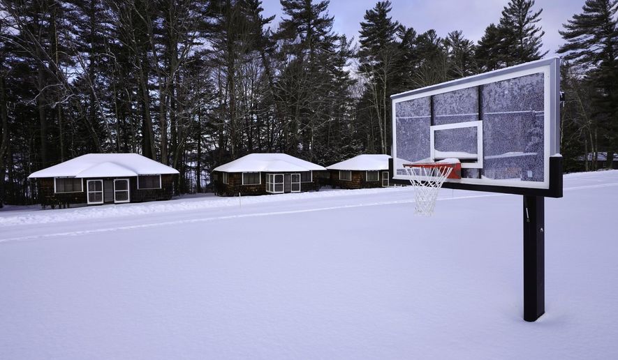Snow covers a basketball court at Camp Fernwood, a summer camp for girls, Saturday, Feb. 20, 2021, in Poland, Maine. Camp directors across the country are feeling more confident about reopening this summer after a pandemic hiatus in 2020, but in some states they are still awaiting guidelines. (AP Photo/Robert F. Bukaty)