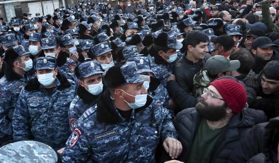 Police wearing face masks to protect against coronavirus, block opposition demonstrators during a rally to pressure Armenian Prime Minister Nikol Pashinyan to resign in Yerevan, Armenia, Tuesday, March 9, 2021. Thousands of opposition supporters blockaded the Armenian parliament building and engaged in occasional scuffles with police on Tuesday to press a demand for the country&#39;s prime minister to step down. (Stepan Poghosyan/PHOTOLURE via AP)