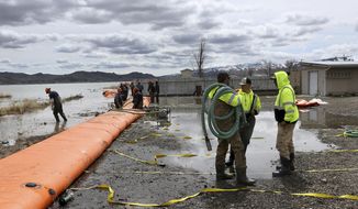 A Washoe County crew installs temporary inflatable barriers in front of homes bordering Swan Lake north of Reno, Nev., to help protect them from floodwaters in Lemmon Valley, on April 3, 2019. Dozens of residents who are suing the city of Reno over flood damage are moving to federal court in a complex case that could cost taxpayers millions of dollars. (Jason Bean/The Reno Gazette-Journal via AP)