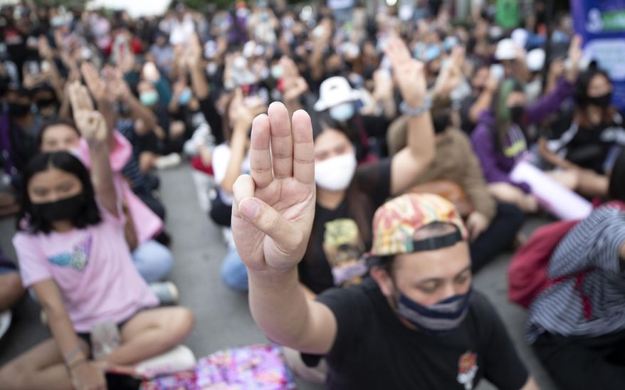 FILE - In this Oct. 23, 2020 file photo, pro-democracy activists flash three-fingered salutes outside Bangkok Remand Prison, in which some of the activists are kept, in Bangkok, Thailand. Thailand is considering an expansion of prison space as it arrests more political prisoners, the Justice Minister Somsak Thepsuthin said Wednesday, March 10, 2021. Somsak said Bangkok Remand Prison and Klong Prem Central Prison, where most recently detained political prisoners are held, become congested when families and supporters come to visit. (AP Photo/Sakchai Lalit, File)
