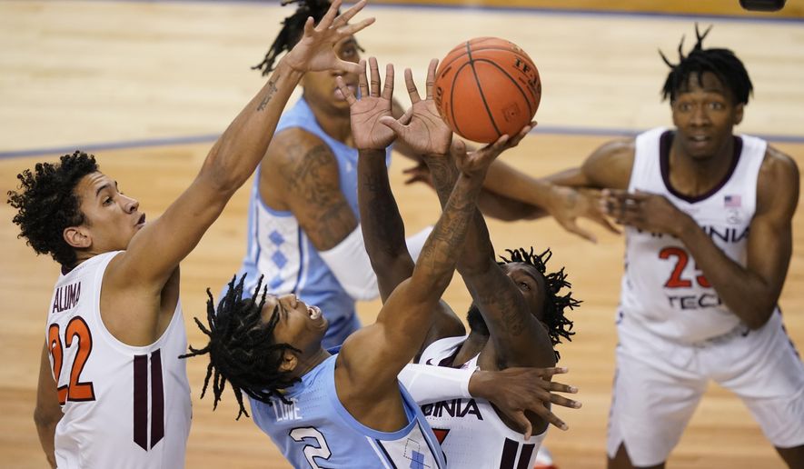 North Carolina guard Caleb Love (2) goes up for a shot as Virginia Tech forward Keve Aluma (22) and teammate guard Tyrece Radford, left, during the second half of an NCAA college basketball game in the quarterfinal round of the Atlantic Coast Conference tournament in Greensboro, N.C., Thursday, March 11, 2021. (AP Photo/Gerry Broome)