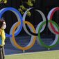 A woman walks past the Olympic rings in Tokyo, Wednesday, March 10, 2021. (AP Photo/Koji Sasahara)