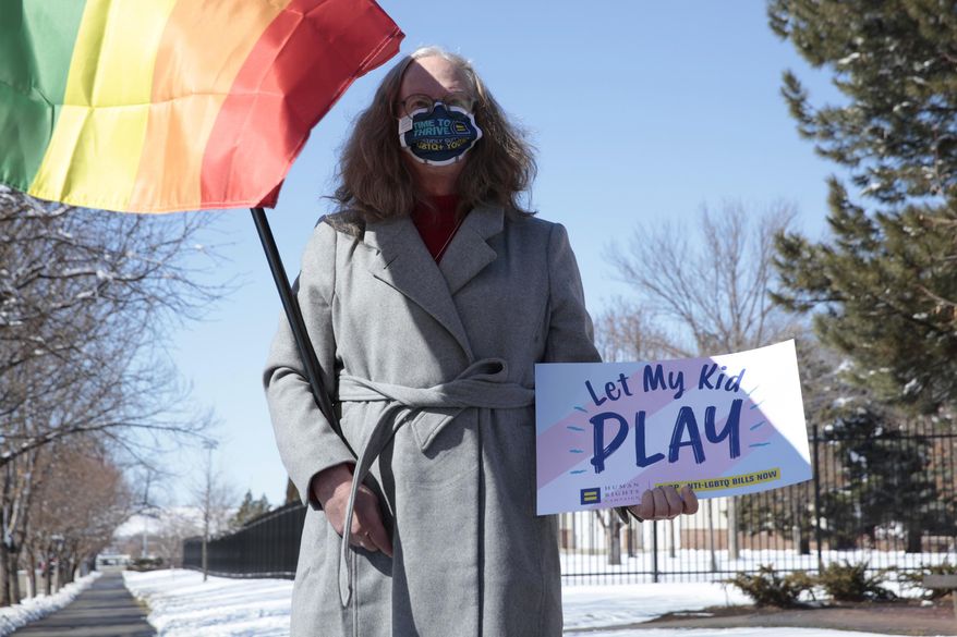 Stephanie Marty demonstrates against a proposed ban on transgender girls and women from female sports leagues outside the South Dakota governor's mansion in Pierre, S.D. on Thursday March 11, 2021. (AP Photo/Stephen Groves)