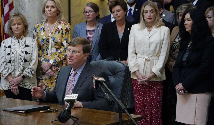 Mississippi Gov. Tate Reeves explains to reporters why he signed the first state bill in the U.S. this year to ban transgender athletes from competing on female sports teams, Thursday, March 11, 2021, at the Capitol in Jackson, Miss. From left standing behind Reeves are Rep. Becky Currie, R-Brookhaven, Rep. Jill Ford, R-Madison, Sen. Jenifer Branning, R-Philadelphia, Sen. Rita Potts Parks, R-Corinth, Rep. Dana McLean, R-Columbus and Sen. Angela Burks Hill, R-Picayune, who were among the legislation's supporters who attended the bill signing. (AP Photo/Rogelio V. Solis)