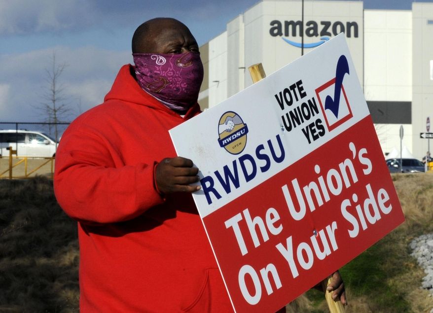 In this Tuesday, Feb. 9, 2021 file photo ,Michael Foster of the Retail, Wholesale and Department Store Union holds a sign outside an Amazon facility where labor is trying to organize workers in Bessemer, Ala. (AP Photo/Jay Reeves, File)  **FILE**