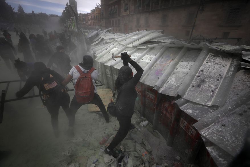Demonstrators attack a barricade protecting Mexico City's National Palace during a march to commemorate International Women's Day and protesting against gender violence, Monday, March 8, 2021. (AP Photo/Rebecca Blackwell)