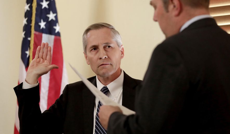 FILE- In this Dec. 19, 2016, file photo, newly-appointed Arizona Supreme Court justice Andrew Gould is sworn in by assistant Arizona Secretary of State Lee Miller, right, at the Capitol in Phoenix. Arizona Supreme Court Justice Andrew Gould announced Friday, March 12, 2021, that he is retiring after just over four years on the court. Gould told Republican Gov. Doug Ducey his last day will be April 1. (AP Photo/Matt York, File)