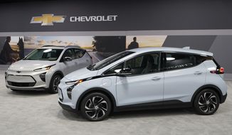 The 2022 Bolt EV, foreground, and EUV are displayed, Thursday, Feb. 11, 2021, in Milford, Mich. Whether people want them or not, automakers are rolling out multiple new electric vehicle models as the auto industry responds to stricter pollution regulations worldwide and calls to reduce emissions to fight climate change.  (AP Photo/Carlos Osorio)